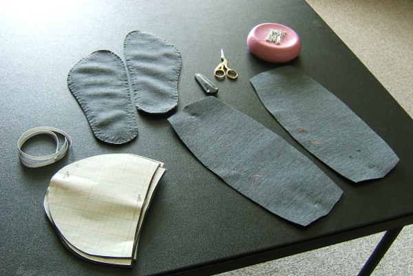 gray slipper parts on card table, with pincushion and scissors